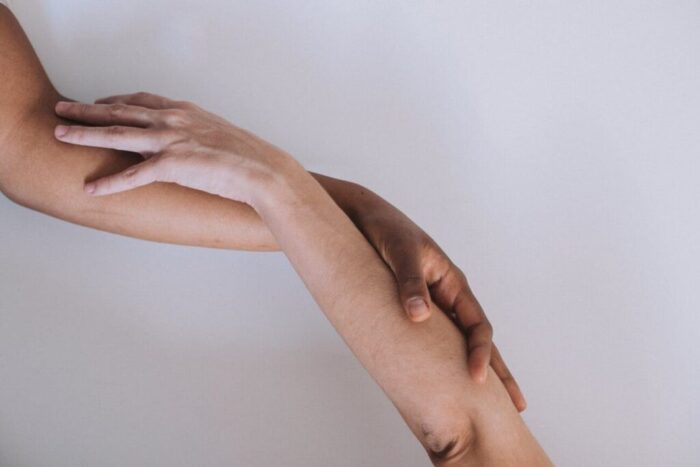 crop hands of anonymous multiethnic couple touching hands in light studio