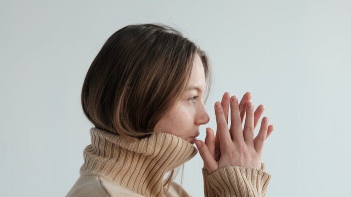 melancholic female in sweater standing with hands together