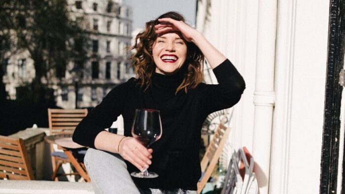 happy woman with red wine on balcony fence
