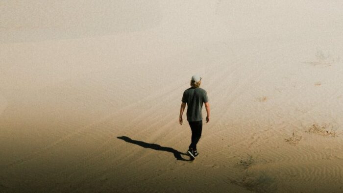 photo of person walking on desert