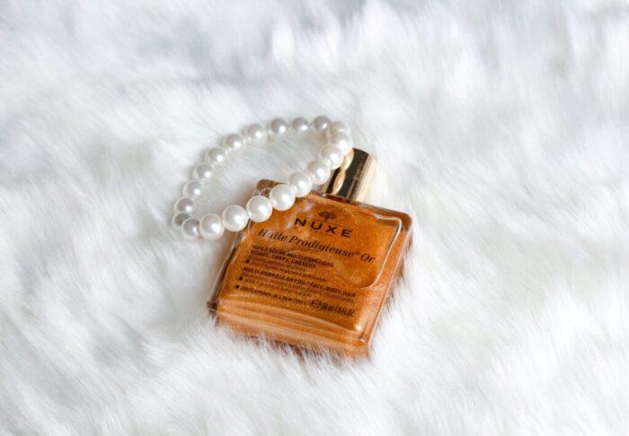 golden face oil in elegant flask on white fluffy fabric