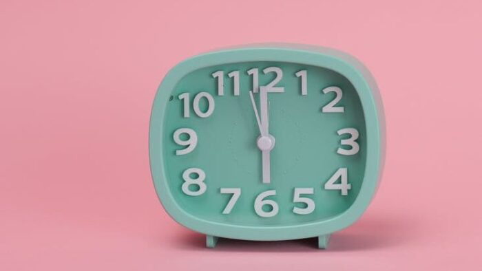 a green analog clock on pink background