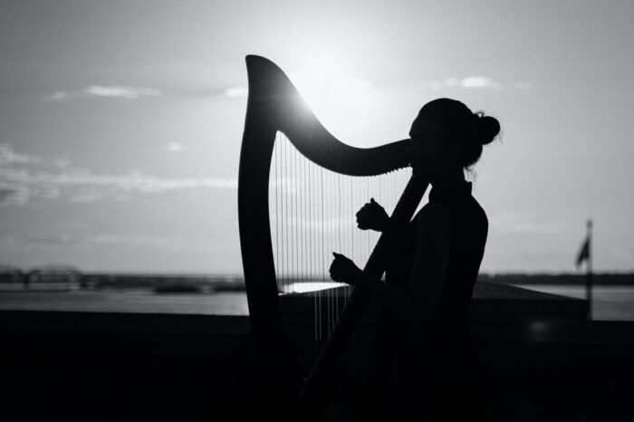 monochrome photo of woman playing harp